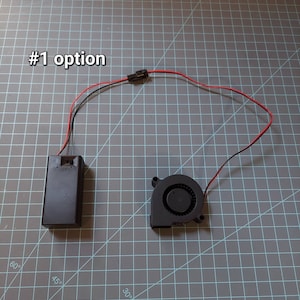 May include: A black battery pack with red and black wires connected to a black fan with a black connector. The text '#1 option' is visible in the top left corner of the image.