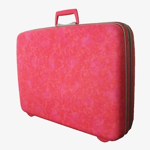 Pu&ograve; includere: Una valigia rigida rettangolare di un vivace colore rosa con una superficie testurizzata e maculata. Il bagaglio presenta una maniglia superiore rosa abbinata e una chiusura a zip color argento lungo tutto il perimetro della valigia.