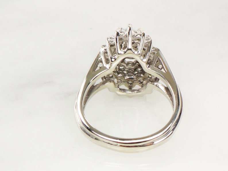 Op de afbeelding: Een zilveren ring met een grote, ronde, veelzijdige steen omringd door kleinere stenen. De ring is gezet in een delicaat, ingewikkeld ontwerp.