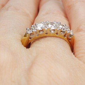 May include: A gold band ring with a row of sparkling diamonds set in a prong setting.