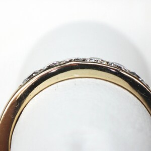May include: A gold band ring with a row of small diamonds set in the band.