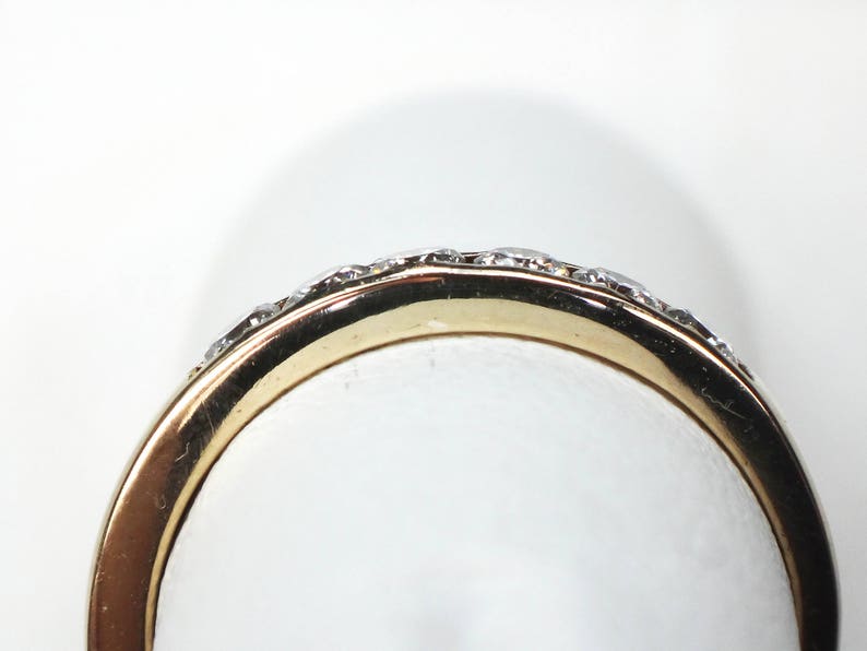 May include: A gold band ring with a row of small diamonds set in the band.