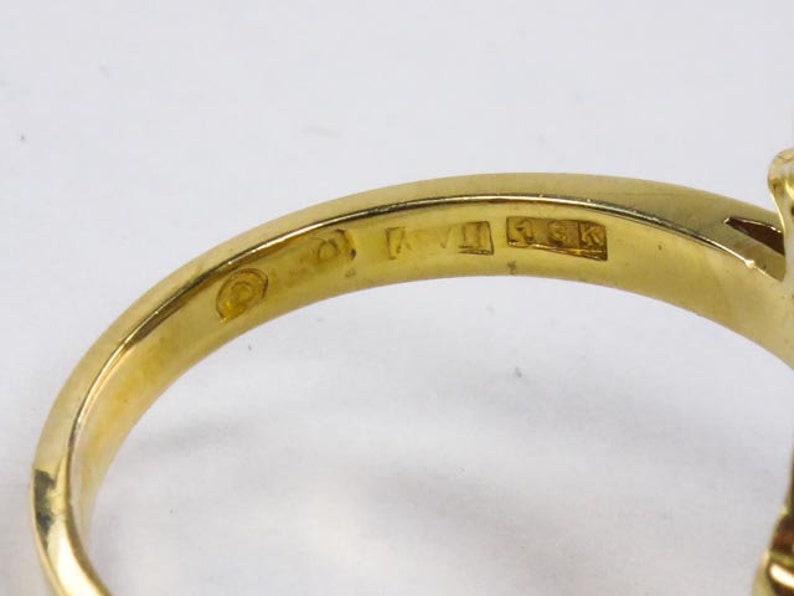 Op de afbeelding: Close-up van de binnenkant van een gouden ring met de markeringen "14K" en "KVI" op de band.