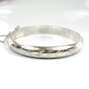 May include: A white ceramic mug with a black handle and the text "But First, Coffee" in a bold, black font. The mug is set against a blurred background, suggesting a cozy setting.