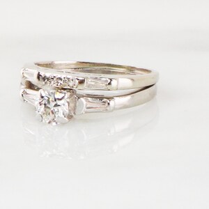 May include: A white gold diamond engagement ring set with a round center stone and baguette side stones.