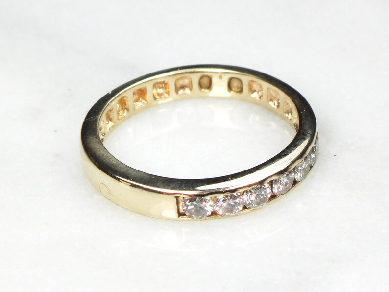 May include: A gold band ring with a row of small, clear diamonds set in the band.