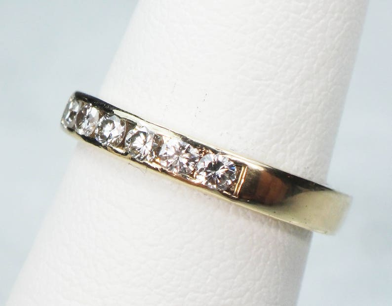 May include: A gold band ring with a row of small, clear diamonds set in the band.