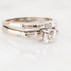 May include: A classic diamond engagement ring set with a round center stone and a matching band with baguette diamonds.