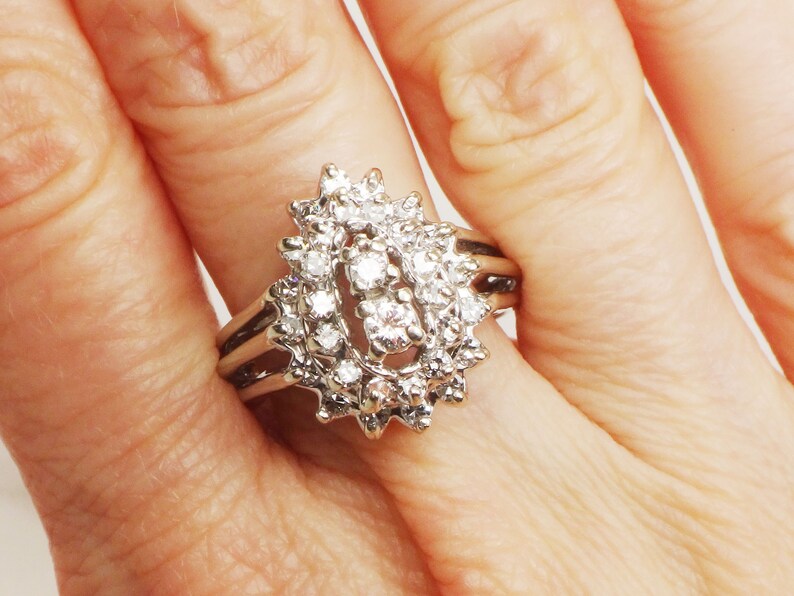 Op de afbeelding: Een zilveren ring met een traanvormig ontwerp bezet met meerdere kleine diamanten.