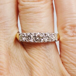 May include: A gold band ring with a row of round, clear diamonds.