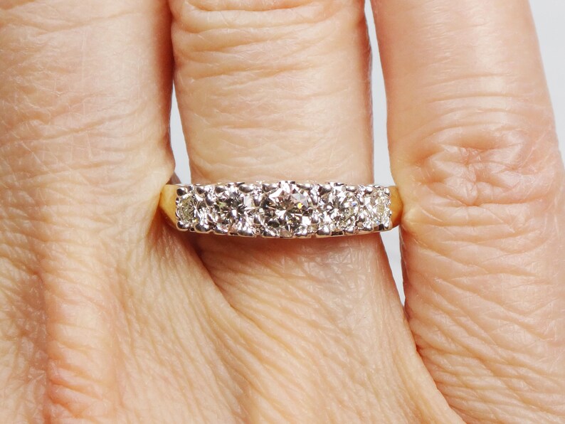 May include: A gold band ring with a row of round, clear diamonds.