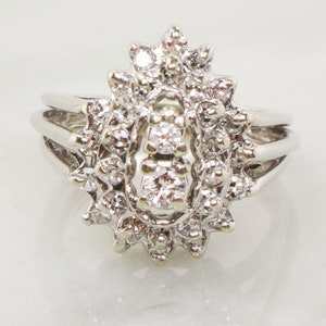 Op de afbeelding: Een zilveren ring met een grote, ovale cluster van diamanten. De ring heeft een delicaat, multiband ontwerp.