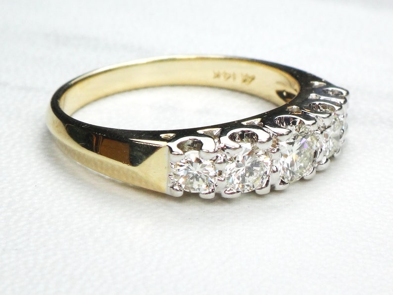 May include: A gold band ring with a row of small, round diamonds set in white metal.