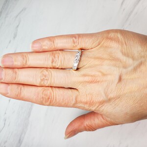 May include: A gold band ring with a row of small, clear gemstones.