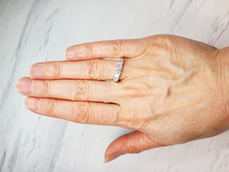 May include: A gold band ring with a row of small, clear gemstones.