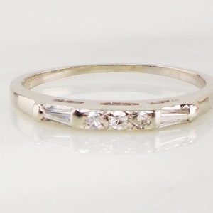 May include: A silver band ring with three round diamonds and two baguette diamonds set in a row.