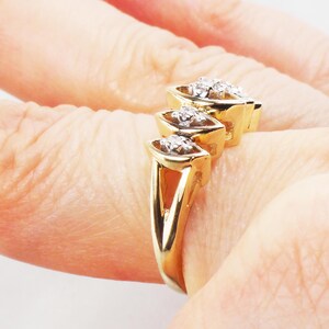 K&ouml;nnte beinhalten: Ein goldener Ring mit drei Marquise-f&ouml;rmigen Diamanten, die in einer Reihe gesetzt sind. Die Diamanten sind mit Krappen gefasst und haben einen klaren, brillanten Schliff.