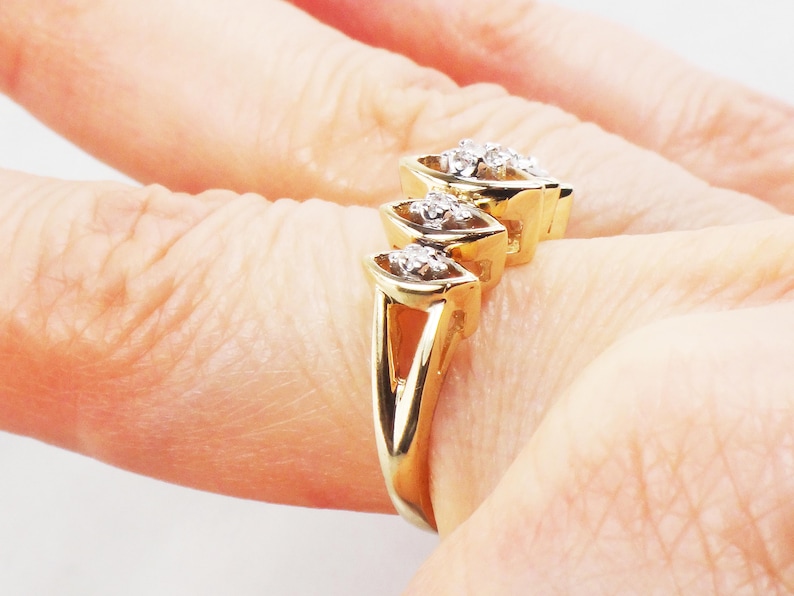 K&ouml;nnte beinhalten: Ein goldener Ring mit drei Marquise-f&ouml;rmigen Diamanten, die in einer Reihe gesetzt sind. Die Diamanten sind mit Krappen gefasst und haben einen klaren, brillanten Schliff.