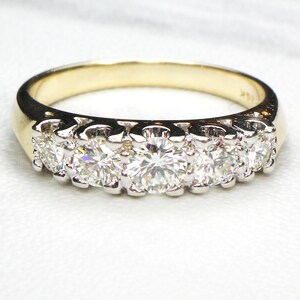May include: A gold band ring with a row of five round diamonds set in white metal.