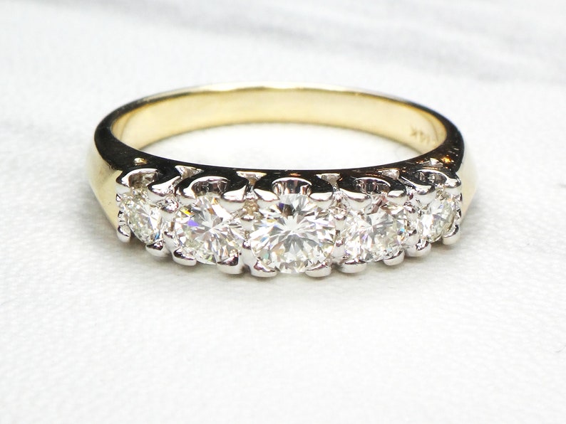 May include: A gold band ring with a row of five round diamonds set in white metal.