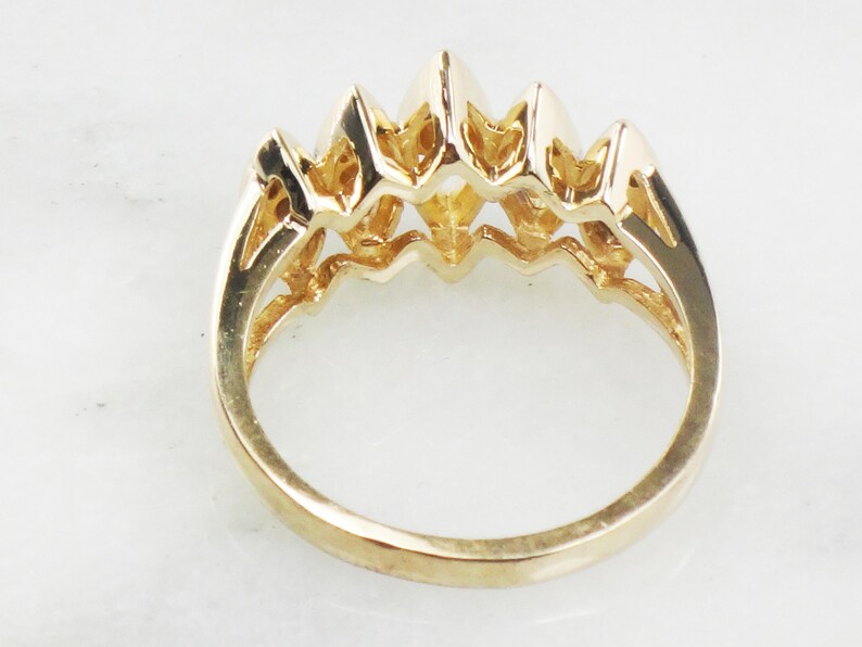 K&ouml;nnte beinhalten: Ein Goldring mit f&uuml;nf in Krappen gefassten Steinen in abgestufter Gr&ouml;&szlig;e. Der Ring ist in einem filigranen, durchbrochenen Design gefasst.