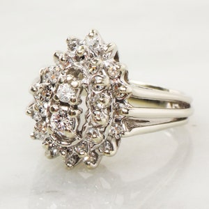 Op de afbeelding: Een zilveren ring met een traanvormige cluster van diamanten. De ring heeft een drievoudig bandontwerp.