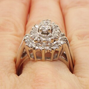 Op de afbeelding: Een zilveren ring met een grote, meerlaagse diamantcluster. De ring is bezet met veel kleine diamanten, waardoor een sprankelend effect ontstaat.