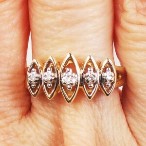 K&ouml;nnte beinhalten: Ein goldener Ring mit f&uuml;nf marquisef&ouml;rmigen Fassungen, jede mit einem kleinen runden Diamanten besetzt. Die Diamanten sind in einer Krappenfassung gefasst.
