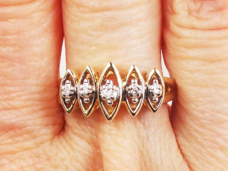 K&ouml;nnte beinhalten: Ein goldener Ring mit f&uuml;nf marquisef&ouml;rmigen Fassungen, jede mit einem kleinen runden Diamanten besetzt. Die Diamanten sind in einer Krappenfassung gefasst.