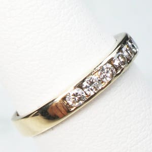May include: A gold band ring with a row of small, clear diamonds set in the band.