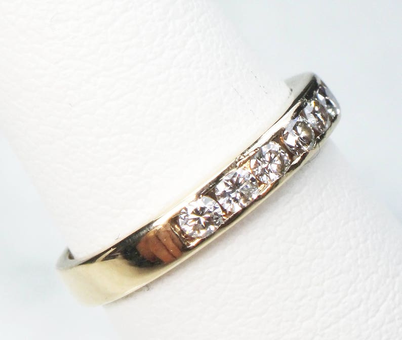 May include: A gold band ring with a row of small, clear diamonds set in the band.