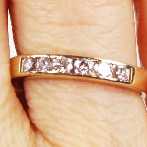 May include: A gold band ring with a row of small, clear diamonds.