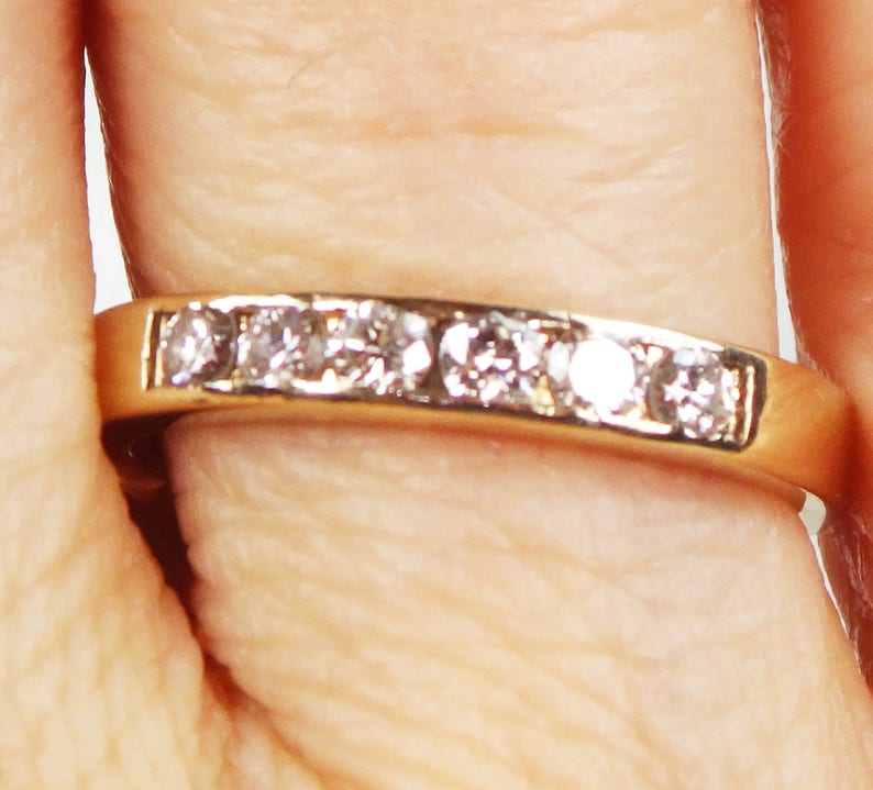 May include: A gold band ring with a row of small, clear diamonds.