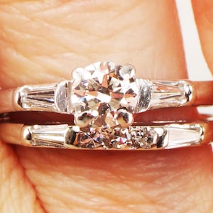 May include: A classic engagement ring set with a round brilliant cut diamond center stone and baguette diamonds on the band.