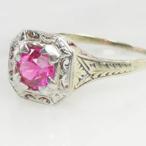 May include: A vintage ring with a pink gemstone set in a filigree design. The ring is made of gold and silver.
