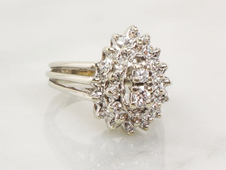 Op de afbeelding: Een zilveren ring met een grote cluster diamanten gezet in een bloemmotief.