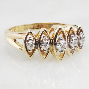 K&ouml;nnte beinhalten: Ein goldener Ring mit f&uuml;nf marquisef&ouml;rmigen Fassungen, jede mit einem kleinen Diamantencluster besetzt.