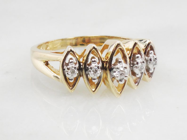 K&ouml;nnte beinhalten: Ein goldener Ring mit f&uuml;nf marquisef&ouml;rmigen Fassungen, jede mit einem kleinen Diamantencluster besetzt.