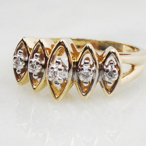 K&ouml;nnte beinhalten: Ein goldener Ring mit f&uuml;nf diamantf&ouml;rmigen Fassungen, jede mit einem kleinen Diamantencluster. Der Ring ist aus zweifarbigem Gold gefertigt, mit einem gelbgoldenen Band und wei&szlig;goldenen Fassungen.