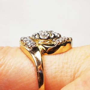 May include: A gold ring with a cluster of clear diamonds set in a twisted band.