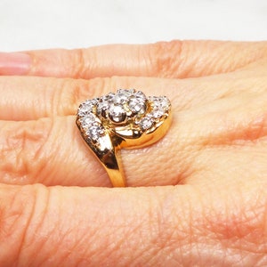 May include: A gold ring with a large, round cluster of diamonds set in the center. The ring is designed with a twisted band.