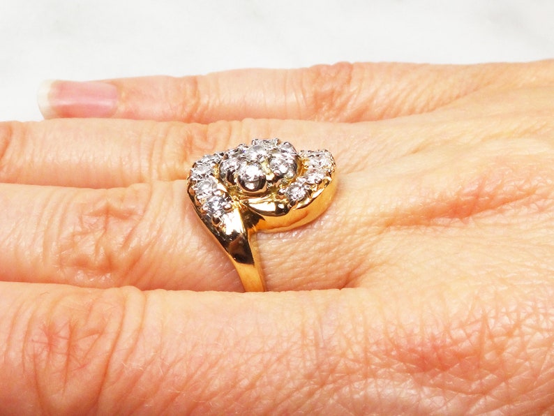 May include: A gold ring with a large, round cluster of diamonds set in the center. The ring is designed with a twisted band.