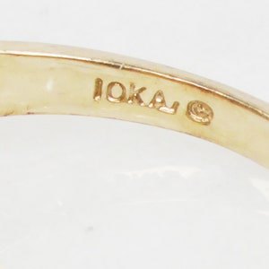 K&ouml;nnte beinhalten: Nahaufnahme der Innenseite eines Goldrings mit der Inschrift "10KA" und einem kleinen Kreis.