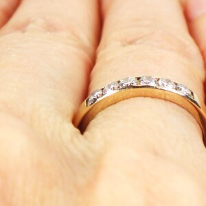May include: A gold band ring with a row of small, clear diamonds set in the band.