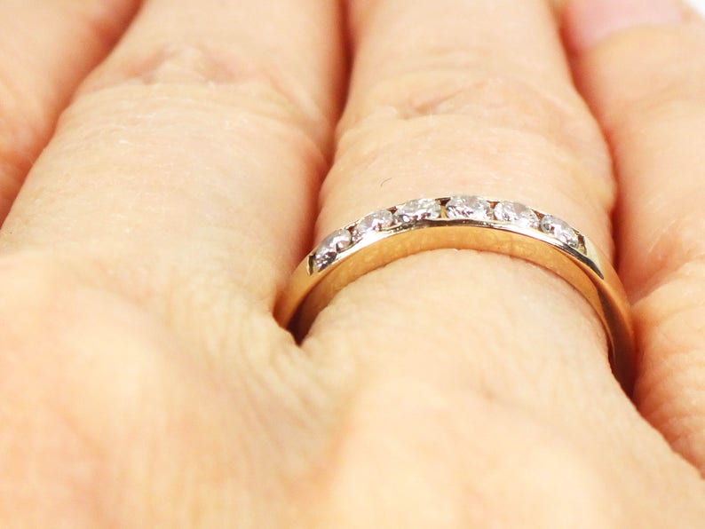 May include: A gold band ring with a row of small, clear diamonds set in the band.