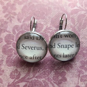 May include: A pair of silver dangle earrings with glass charms featuring text from the Harry Potter book series. The text on the left charm reads "said Dumbledore" and "Severus, once after". The text on the right charm reads "don't worry," and "Snape let moments later."