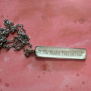 Collar colgante "La Voz de la Sombra no es Real" hecho con páginas del libro Phantasma
