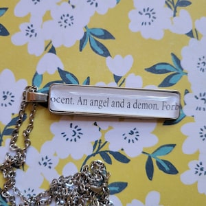 An Angel and a Demon pendant necklace made with Haunting Adeline book pages