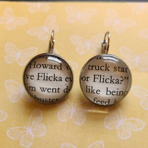May include: A pair of silver earrings with glass cabochons featuring text from the book "Flicka" by Mary O'Hara. The text on the left earring reads "Howard ve Flicka ev m went d buster" and the text on the right earring reads "truck star or Flicka?" like being feed b".