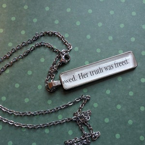 Puede incluir: Un collar de cadena de plata con un colgante rectangular que dice "owed. Her truth was freed."